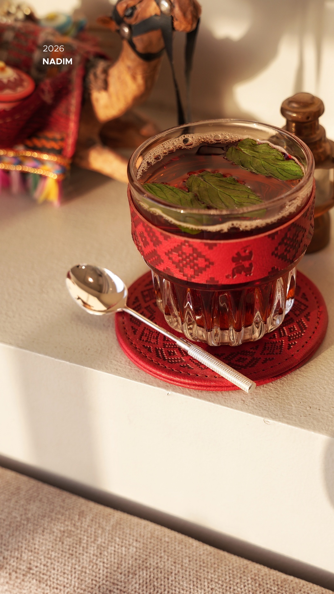 NADIM red tea in a patterned glass, with the tag beside it